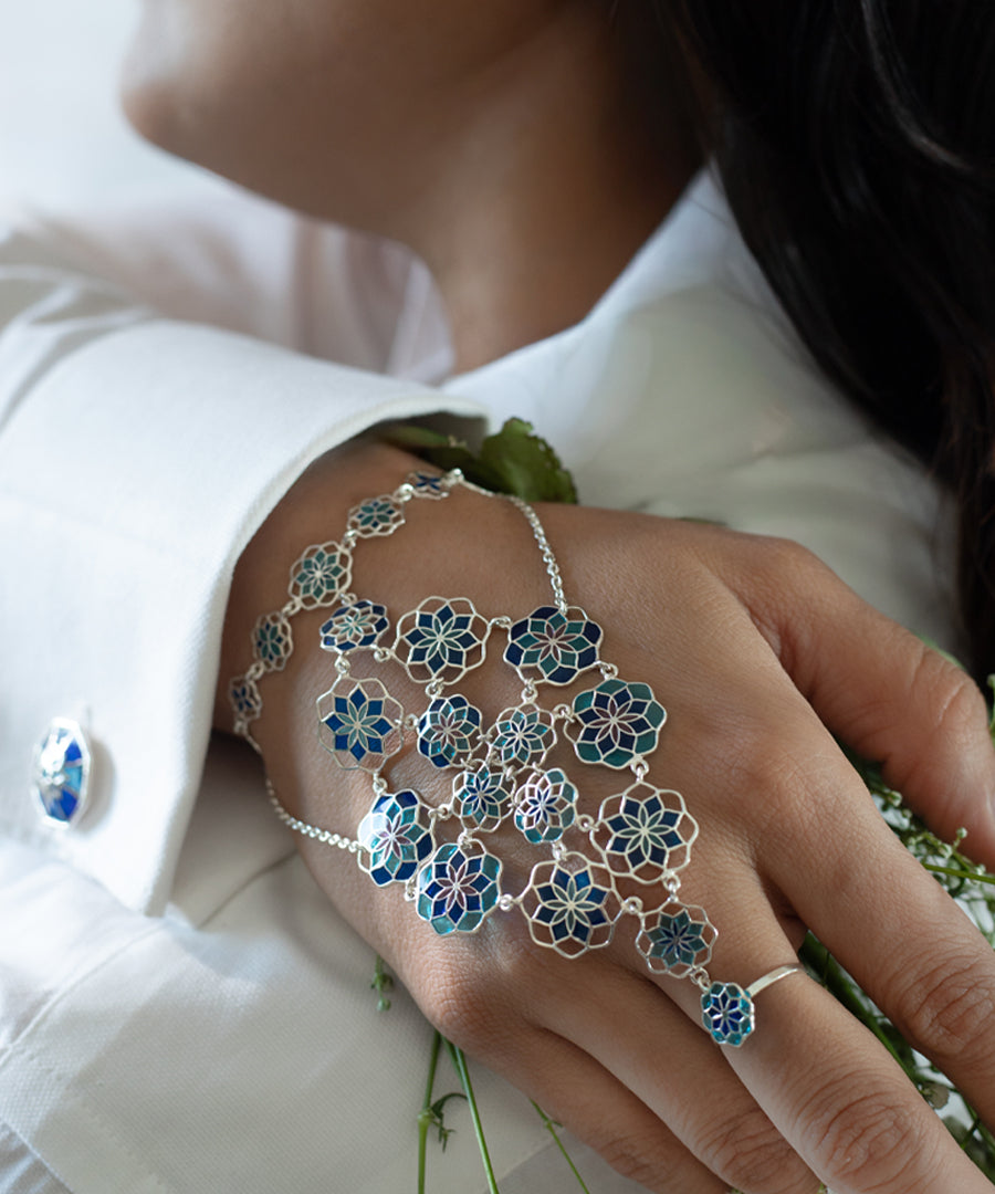 Close-up of a hand wearing a floral silver and blue bracelet