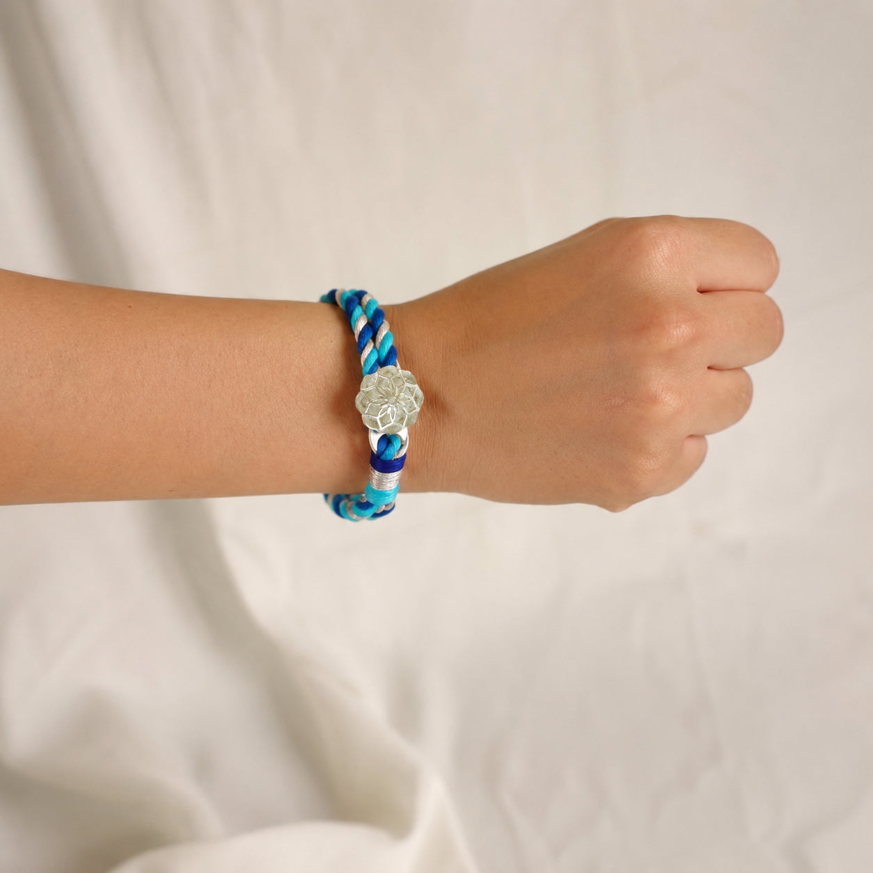 Handcrafted Rakhi for Bhabhi with silk threads, Zari work, and a silver centerpiece.