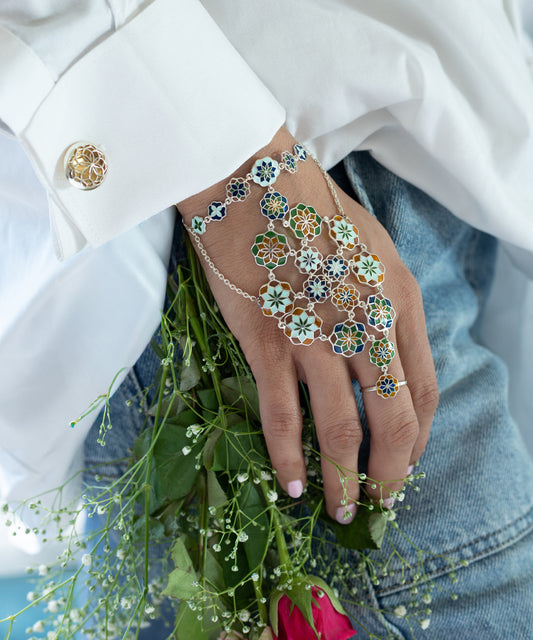 Hand wearing a floral bracelet with enamel work on it